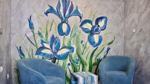 A room with two blue armchairs, a small side table, and a wall mural of blue flowers.