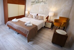 A hotel room with a double bed, two bedside tables, a chair, and a small side table.