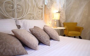 A bed with patterned pillows, a bedside lamp, and a yellow armchair in a room with a marble wall.