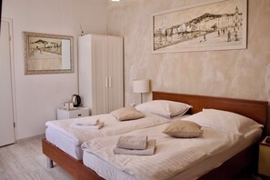 A double bed with white linens and pillows, a bedside table with a lamp, a wardrobe, and two framed artworks on the wall. - Luxury Lidija Rooms (Split)