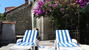 Two white lounge chairs with blue and white striped covers, positioned on a concrete surface with a colorful inflatable pool nearby.