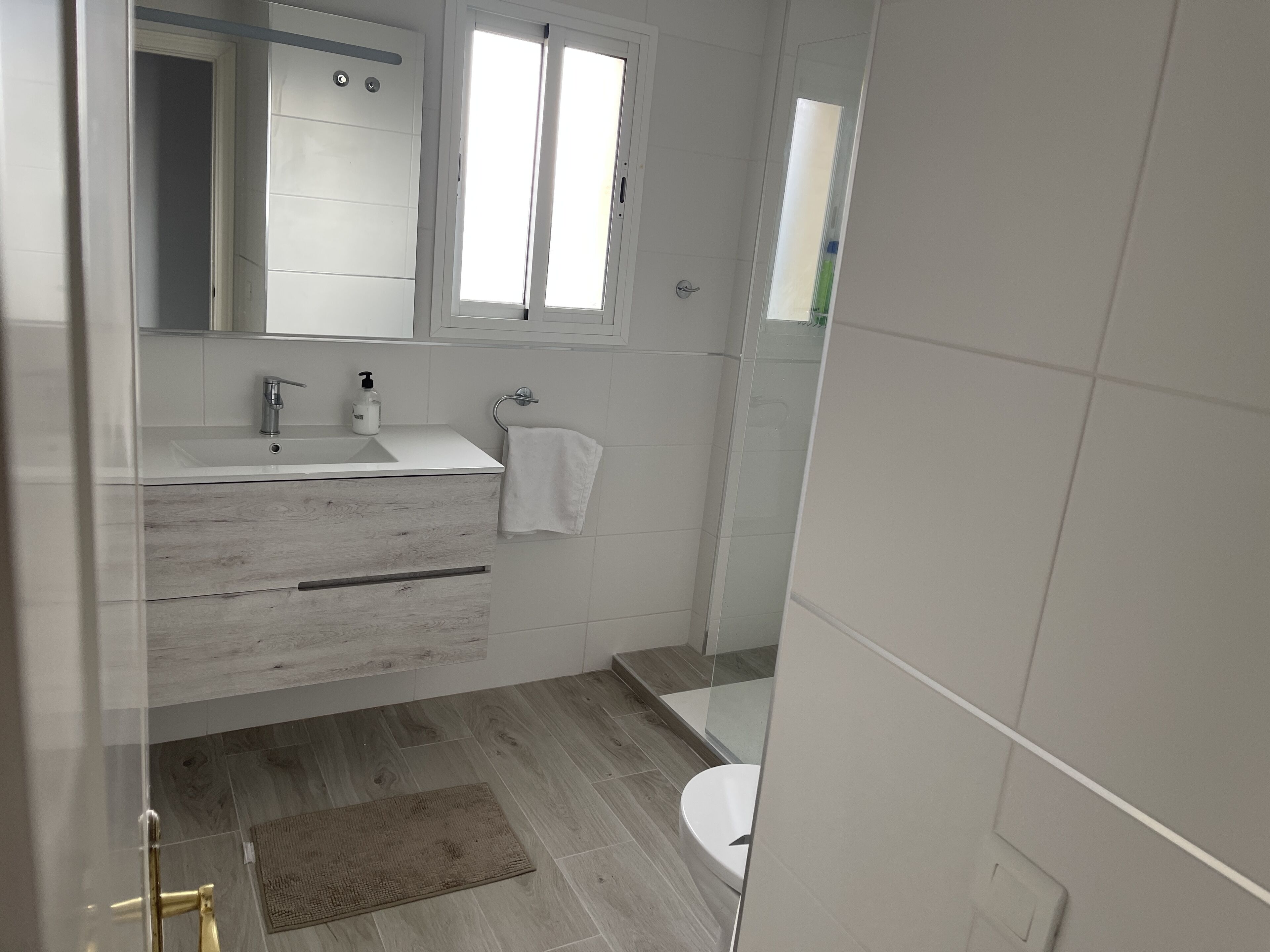 Un baño moderno con lavamanos, espejo y retrete blancos.