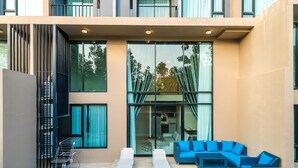 Um edifício moderno com piscina, móveis de exterior azuis e grandes janelas.