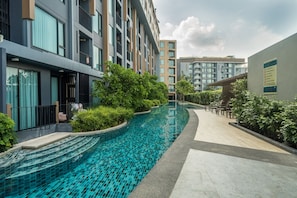 Um hotel moderno com piscina, rodeado por vegetação e arquitetura contemporânea.
