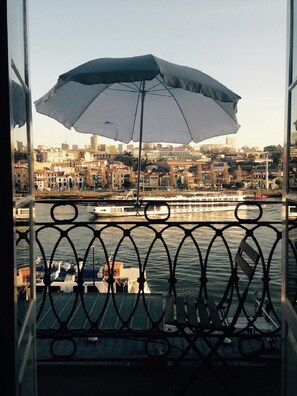 Ein Balkon mit Metallgeländer und Blick auf eine städtische Skyline am Wasser.