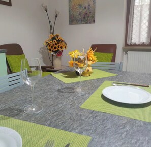 Une table à manger dressée avec une assiette, deux verres à vin et un vase rempli de fleurs.