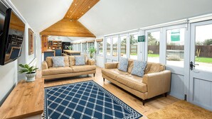 A spacious living area with two beige sofas, a wooden coffee table, and a blue patterned rug. - Beautiful cabin near Bath with heated swimming pool sleeps up to 17 people (Bristol)
