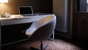 A modern office space with a desk, chair, laptop, and a radiator.