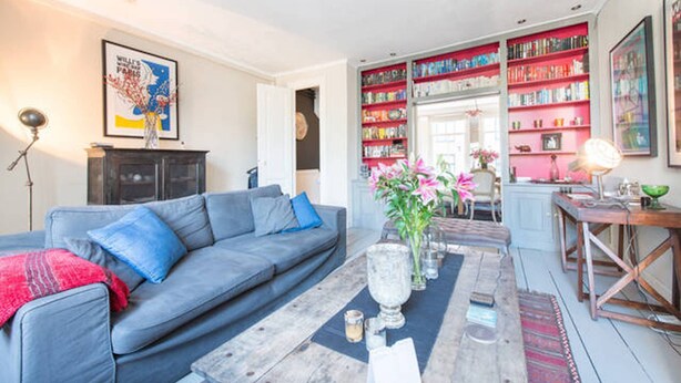 Un salon avec un canapé bleu, une table basse et une bibliothèque remplie de livres.