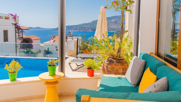Ein Balkon mit Meerblick, eine Couch mit Kissen und Topfpflanzen.