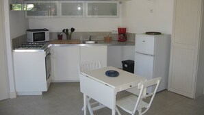 Cocina compacta con estufa a gas, microondas, pileta y heladera pequeña.