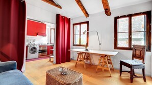 A room with a wooden ceiling, a dining table with chairs, a kitchen area, and a window with curtains. - BRAGORA SMOOCHY ATTIC VENICE M0270423479 (Venice)