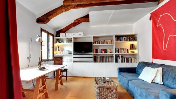 A modern living room with a white sofa, a wooden dining table, and a TV. - BRAGORA SMOOCHY ATTIC VENICE M0270423479 (Venice)