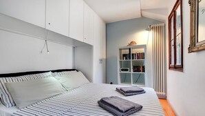 A bedroom with a bed, a bookshelf, and a radiator. - BRAGORA SMOOCHY ATTIC VENICE M0270423479 (Venice)