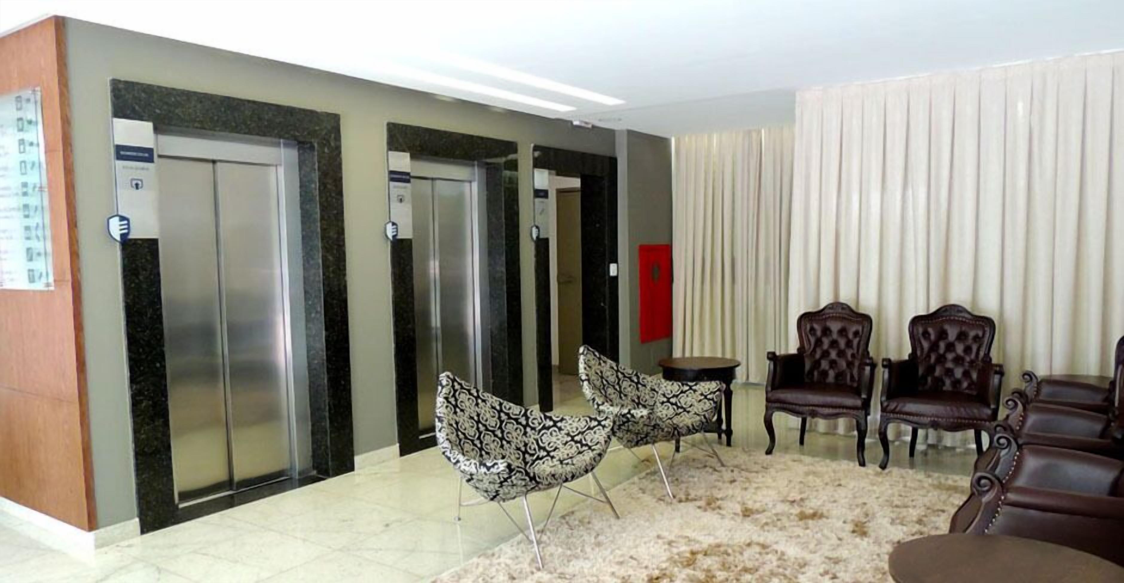 Un vestíbulo con dos ascensores, una zona de estar con sillones estampados y una alfombra de piel.