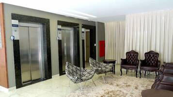 Un vestíbulo con dos ascensores, una zona de estar con sillones estampados y una alfombra de piel.