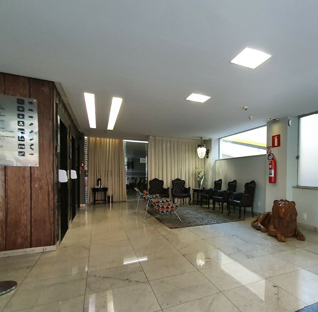 Um saguão de hotel com balcão de recepção, área de estar e extintor de incêndio.