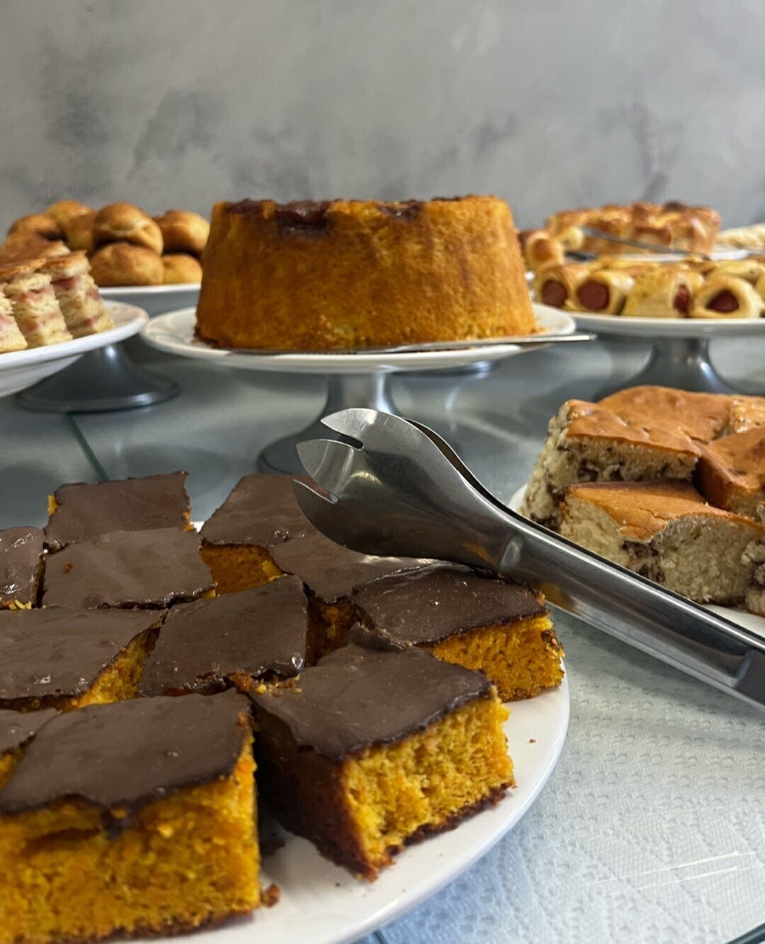 A variety of desserts on a buffet table, including a bundt cake, chocolate-topped squares, and other baked goods.