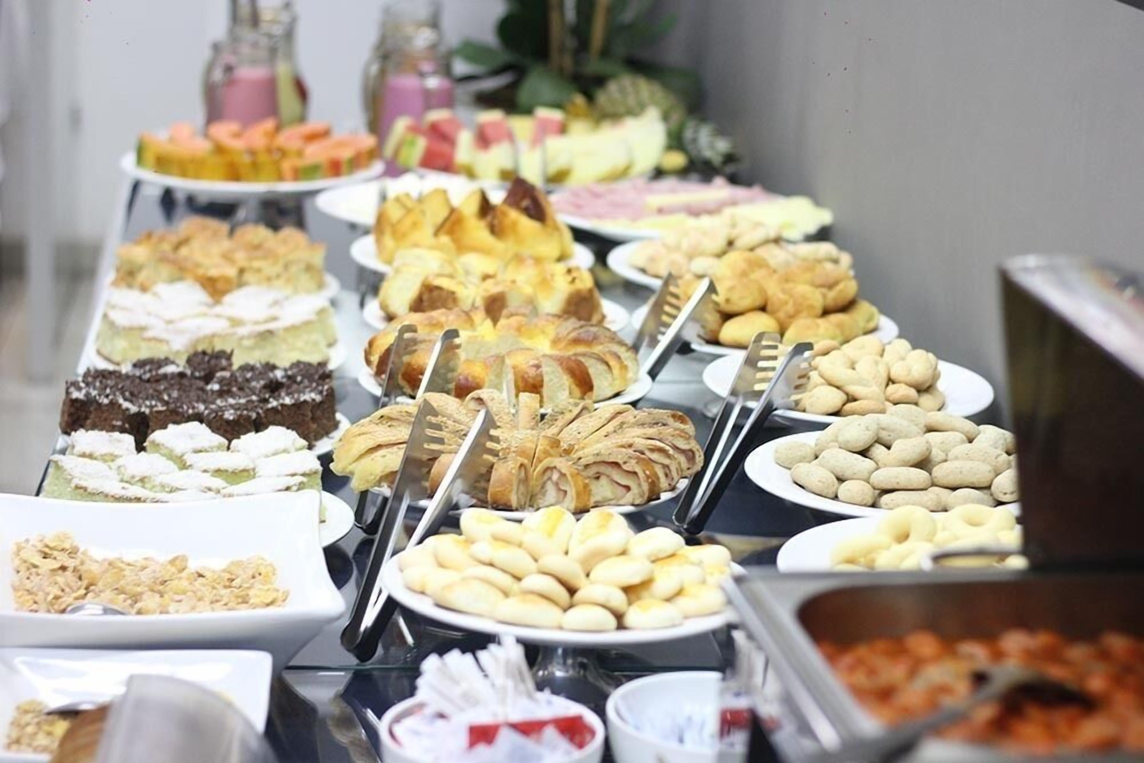Un bufé con diferentes opciones de comida, incluyendo pasteles, sándwiches y frutas.