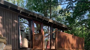 A wooden deck with a stone wall, wooden steps, and a wooden railing. - SLOY CABIN is a charming cabin in a stunning loch side location, with hot tub. (Taynuilt)