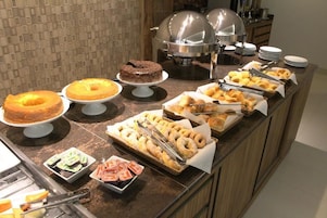 Un bufé con una variedad de alimentos, incluyendo pasteles, donas y productos de pastelería.