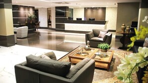 A modern hotel lobby with a reception desk, seating area, and a large mirror. - Hotel Solaris (Formosa)