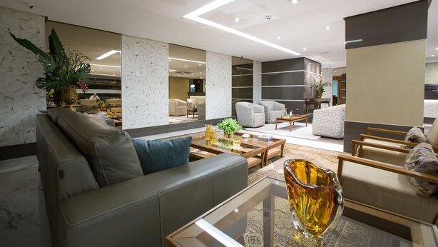 A modern living room with a sofa, armchairs, and a coffee table. There are plants and decorative items on the coffee table. - Hotel Solaris (Formosa)
