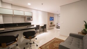 A modern kitchen with a black countertop, two black office chairs, a grey sofa, and a decorative rug. - Hotel Solaris (Formosa)