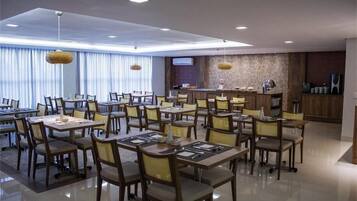 Un comedor moderno con varias mesas y sillas, una barra y una zona de cocina.