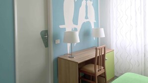 Una habitación con pared azul, un escritorio de madera con dos lámparas, un armario verde y un equipo de aire acondicionado blanco.