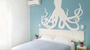 Un dormitorio con cama, aire acondicionado de pared y un gran mural de pulpo.
