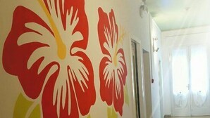 Un pasillo con un cuadro de grandes flores rojas y amarillas en la pared.