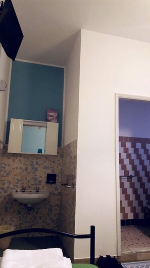 Un bagno con un lavandino, uno specchio e un armadietto sopra. Sul pavimento, una sedia e un asciugamano.
