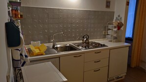 A kitchen with a stainless steel sink, a kettle, and a stove. There are cabinets and a countertop. - apartment/ flat - Venezia (Venezia)