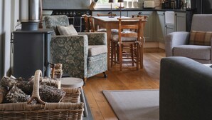 Una sala de estar acogedora con chimenea, comedor y cocina con un ventanal grande.