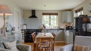 Una cocina acogedora con comedor, que incluye estufa, horno, refrigerador y una ventana con persianas.