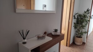 Et moderne badeværelse med et hvidt toiletbord, et spejl, en lille potteplante og en dekorativ glasbeholder.