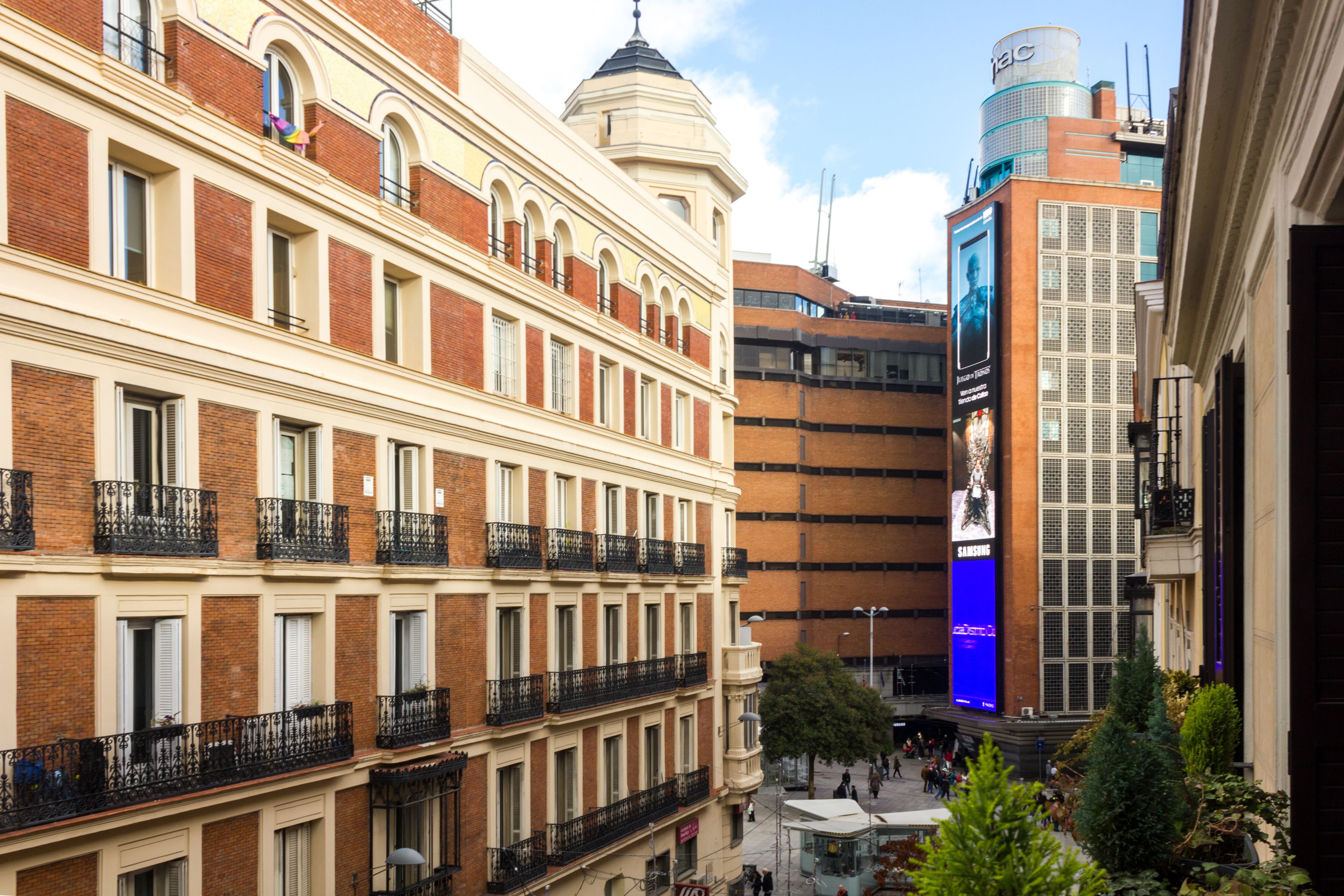 Um edifício de vários andares com estilo arquitetônico clássico, apresentando varandas com grades de ferro forjado e uma cúpula central.