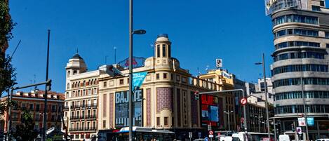 A busy urban street with historic buildings, including a prominent building with a dome and a modern skyscraper.