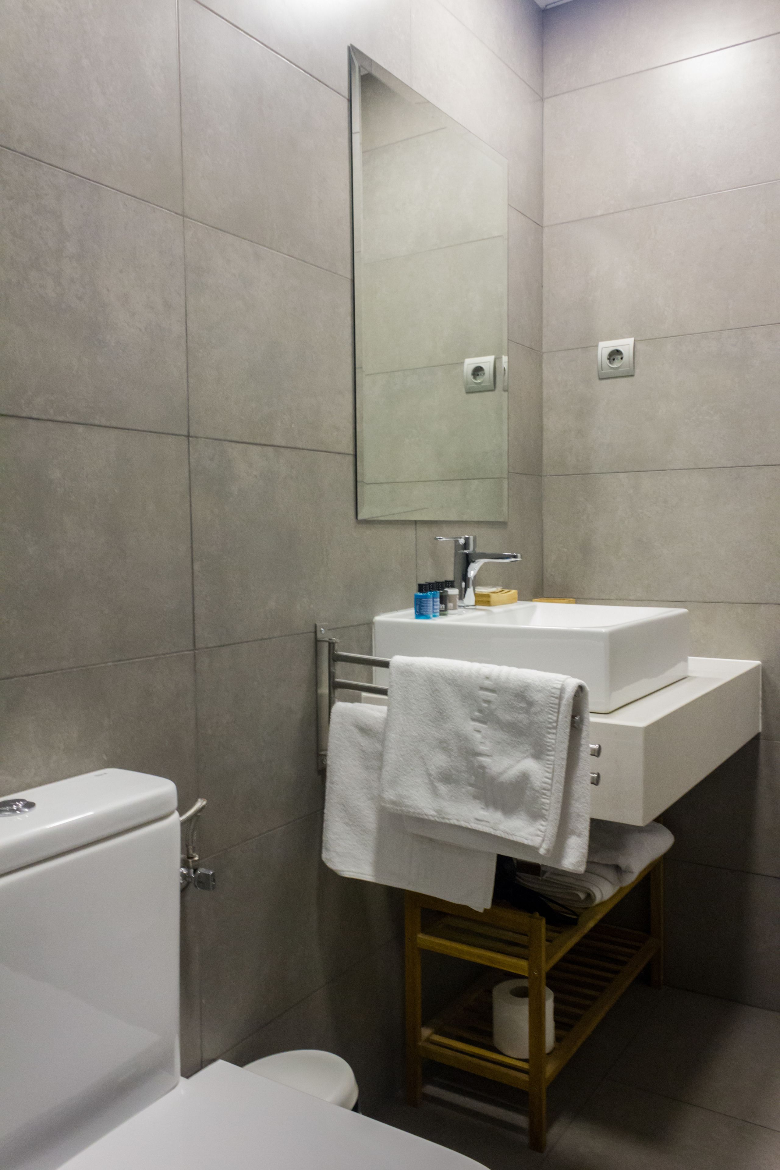 Un baño moderno con un lavamanos, espejo y retrete blancos.