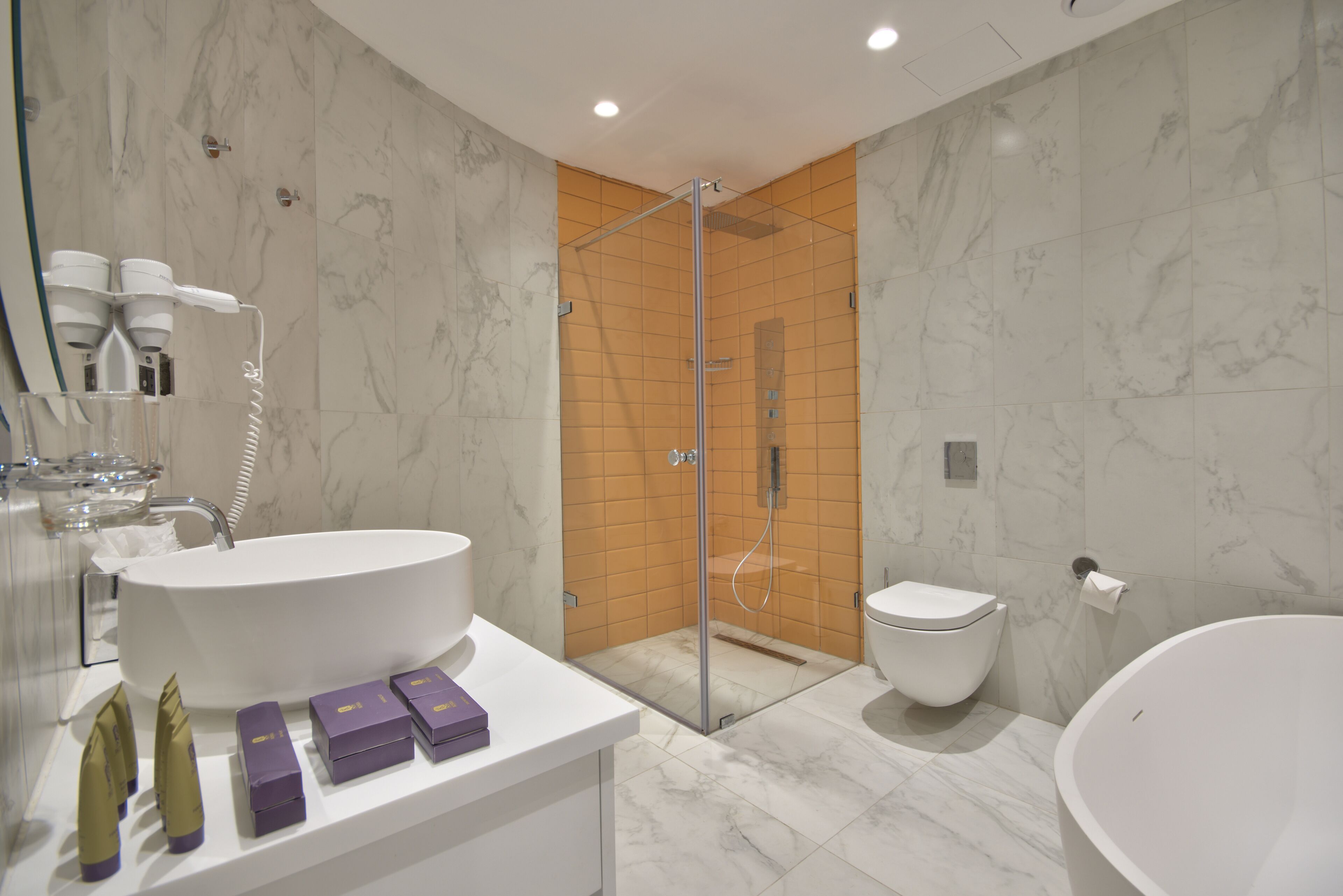 Ein modernes Badezimmer mit einer großen weißen Badewanne, einer separaten Toilette und einer Duschkabine aus Glas.