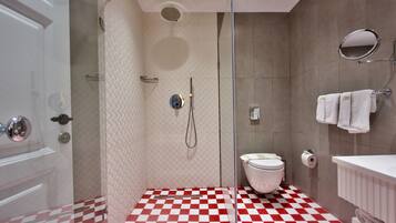 Ein Badezimmer mit Schachbrettboden, einer Duschkabine aus Glas, einer Toilette und einem weißen Waschbecken mit Spiegel.
