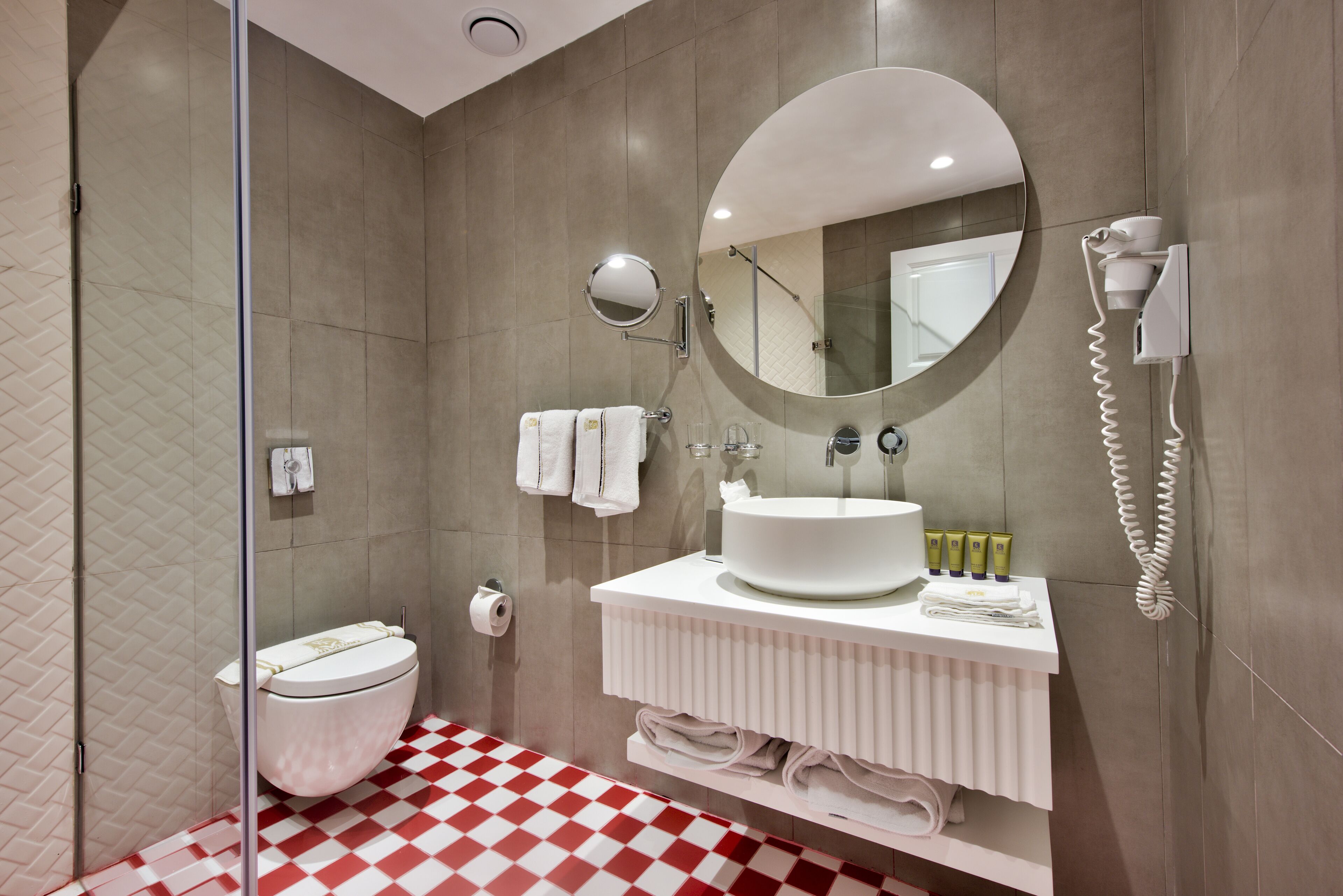 Un baño moderno con un espejo grande, un lavabo redondo y un inodoro.