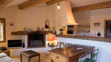 Un salon chaleureux avec une cheminée, un téléviseur et un coin repas comprenant une table et des chaises en bois.