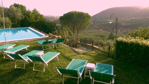 A pool area with green lounge chairs and a view of a hilly landscape. - PROMOTION Typical Tuscan dwelling, house with garden among olive trees (Calci)
