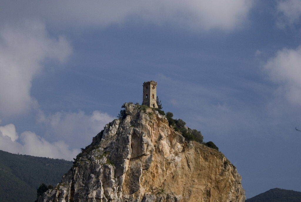 Ein felsiger Hügel mit einem Turm auf der Spitze.