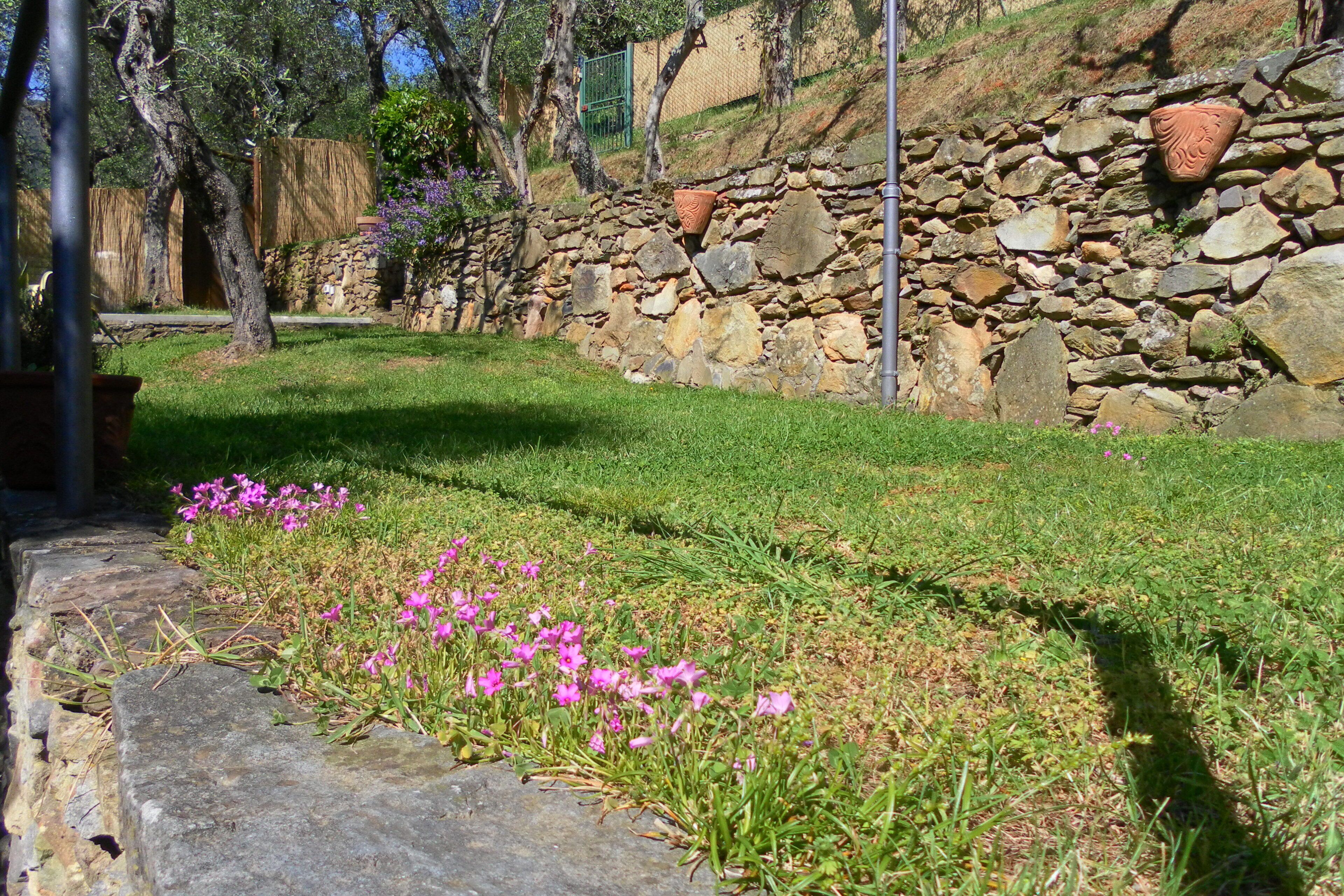 Eine Steinsäule mit Blumenbeet und Rasenfläche.