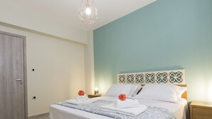 Un lit bien fait, avec une couvre-lit à motifs, une tête de lit en bois et une table de chevet surmontée d’une lampe.