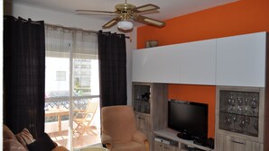Ein Wohnzimmer mit Fernseher, Holzschränken und Deckenventilator.