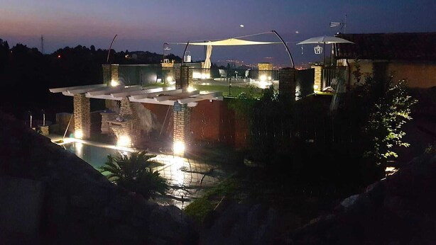 Un espace piscine sur le toit, agrémenté d’une pergola, d’un éclairage extérieur et offrant une vue sur le paysage environnant.